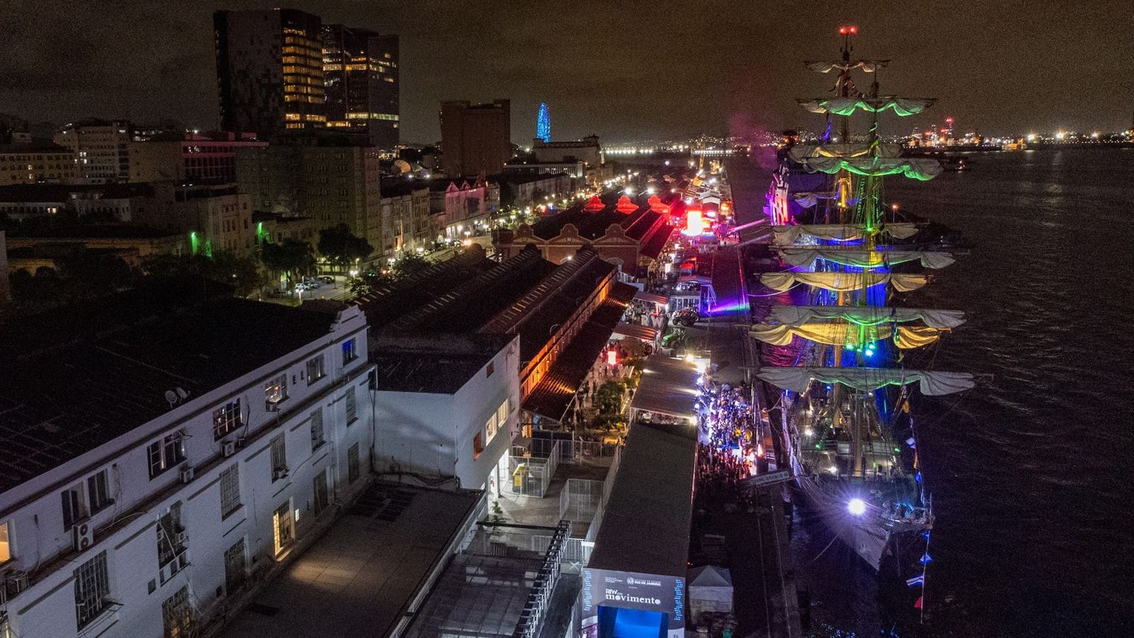 Aerial night view of Pier Mauá with Cisne Branco lit up in color and NAM Atlântico behind it