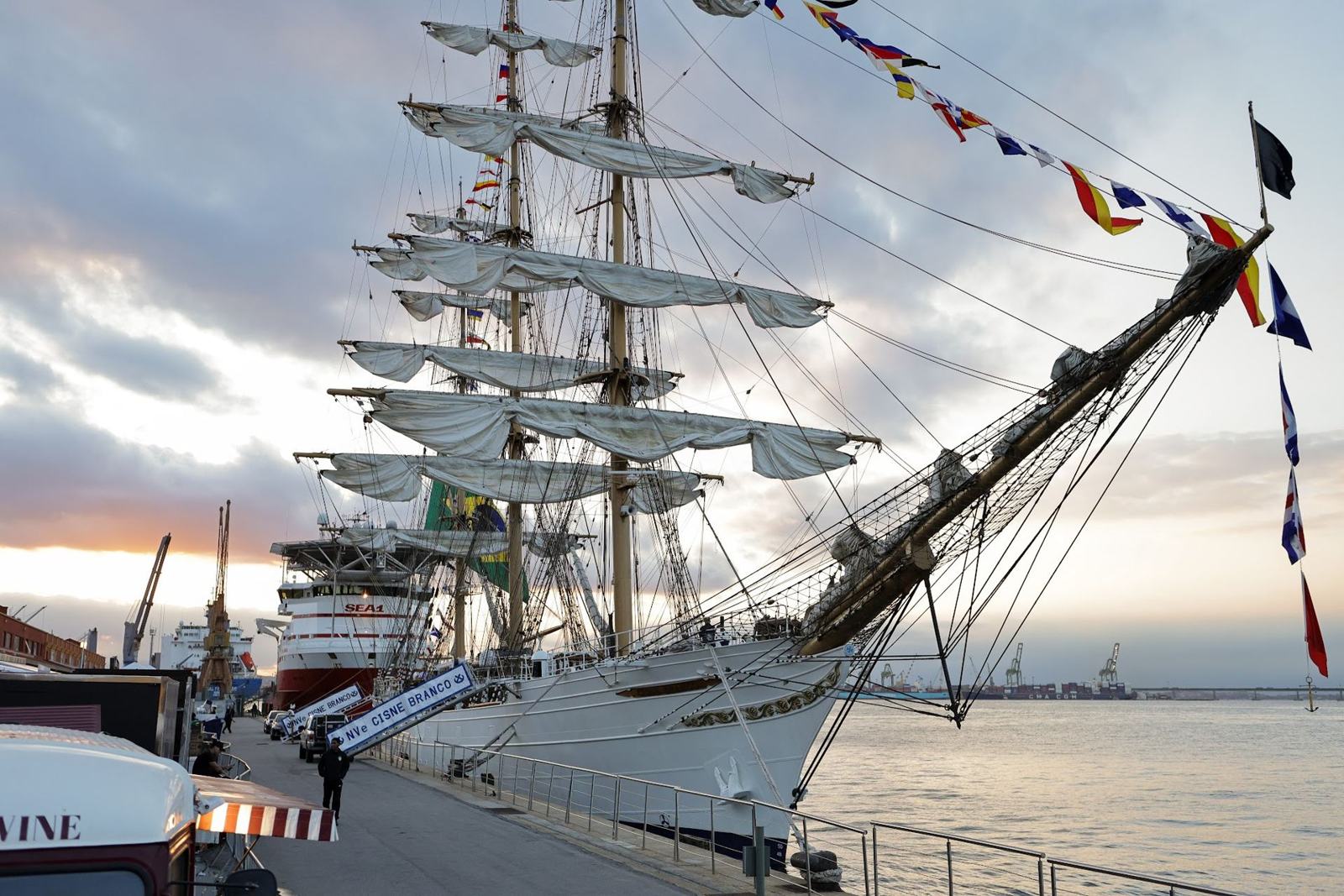 The tall ship Cisne Branco docked at Pier Mauá, sails furled and flags flying at dusk