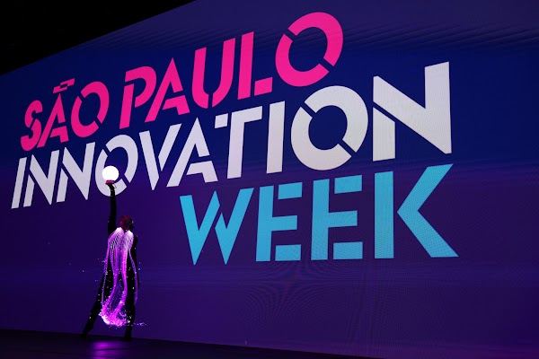 Dancer in a light costume in front of the São Paulo Innovation Week backdrop at the opening